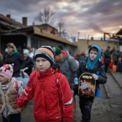 Діти з огорненими очима стоять на залишках війни