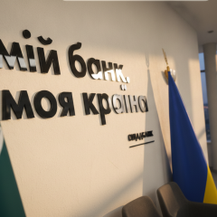 Логотип Ощадбанка на фоне денежных купюр